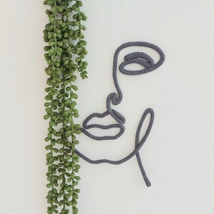 Minimalist modern wall hanging half face, made of knitted cord and wire