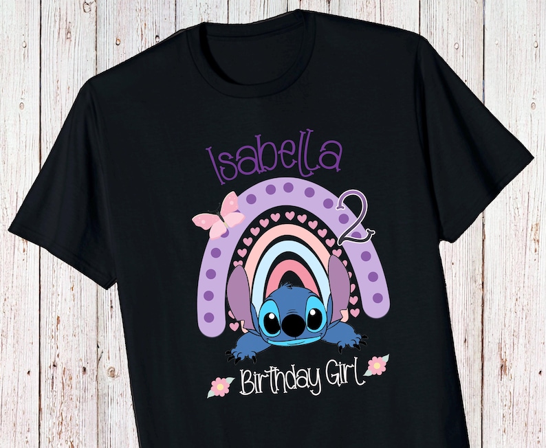 May include: Black t-shirt with a purple, pink, and blue rainbow with a Stitch character peeking out from behind it. The text "Isabella 2 Birthday Girl" is printed on the shirt.