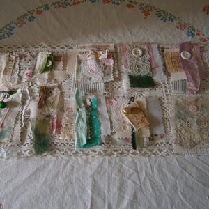 May include: A display of fabric samples, each with distinct textures and decorations. The samples feature lace, ribbons, and buttons in diverse colours, such as white, green, and pink. Some samples have small tags and pins attached. The arrangement is on a white lace-edged surface.