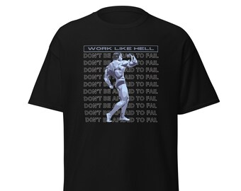 Pode incluir: Camiseta preta com uma ilustração estilizada de um fisiculturista. A camiseta inclui o texto "WORK LIKE HELL" acima da imagem e a frase "DON'T BE AFRAID TO FAIL" repetida verticalmente.