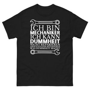 May include: Black t-shirt with white text that reads "Ich bin Mechaniker Ich kann Dummheit nicht reparieren aber ich kann reparieren was Dummheit macht". The text is surrounded by two wrench images.