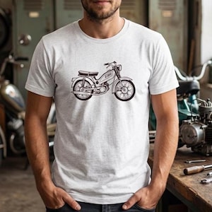 Op de afbeelding: Een lichtgrijs gemêleerd T-shirt met korte mouwen en een zwarte lijntekening van een vintage bromfiets in het midden op de borst. De afbeelding toont het zijprofiel van de gemotoriseerde fiets met spaakwielen, een zadel en een stuur.