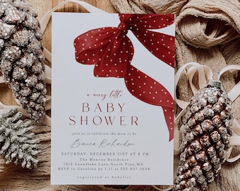 Peut inclure: Une invitation à une baby shower avec une illustration d'un nœud rouge à pois. Le texte de l'invitation se lit « a merry little BABY SHOWER » et comprend les détails de l'événement. Des ornements de pommes de pin décoratifs et du tissu entourent l'invitation.