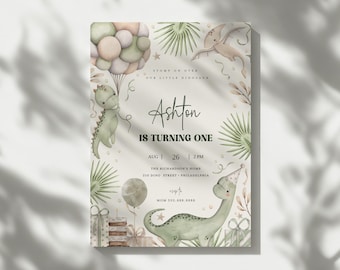 May include: A light beige invitation card with a dinosaur theme. The card features the text "Ashton is turning one" and includes details for a party on August 26th at 2 PM. The design incorporates illustrations of dinosaurs, balloons, and gifts.