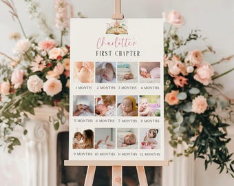 May include: A wooden easel holds a sign with the text "Charlotte's FIRST CHAPTER." The sign showcases a collage of baby photos, each labelled with a month from 1 to 12. The sign is decorated with floral elements.