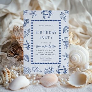 Puede incluir: Una tarjeta de invitación blanca con un tema náutico azul. La tarjeta presenta ilustraciones de conchas marinas, estrellas de mar y cangrejos. El texto en la tarjeta dice "Birthday Party" e incluye los detalles del evento. La tarjeta está rodeada de conchas marinas y perlas.