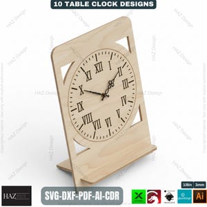 May include: A wooden table clock with a Roman numeral clock face. The clock is light brown and has a rectangular base. The text "10 TABLE CLOCK DESIGNS" is at the top. The clock is approximately 8 inches tall.