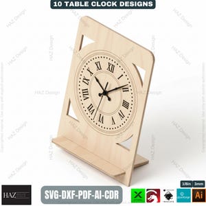 May include: A wooden table clock with a Roman numeral clock face. The clock is light-colored with a rectangular frame and a shelf at the bottom. The text "10 TABLE CLOCK DESIGNS" is at the top. The clock is 1/8 inch or 3mm thick.