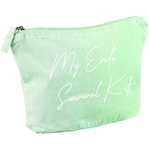 May include: A light green canvas cosmetic bag with a zipper closure. The bag features the text "My Endo Survival Kit" in a white script font. The bag is designed to hold personal care items.