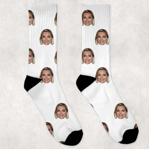 May include: A pair of white socks with a repeated pattern of a woman's face. The socks have black heels and toes.