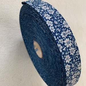 Puede incluir: Un rollo de cinta azul y blanca con estampado floral. La cinta está enrollada y el extremo es visible.