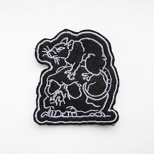 May include: Black and white embroidered patch of a rat sitting on a skull. The rat is outlined in white and the skull is filled in black.