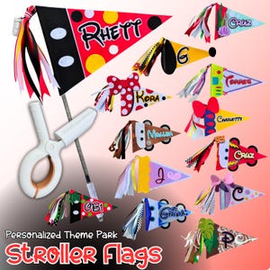 May include: A collection of personalized stroller flags in various designs and colors. Each flag features a name, decorative elements, and colorful ribbons. The flags are attached to a white clip and pole, perfect for theme park outings.