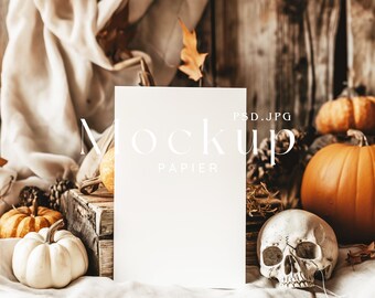 Op de afbeelding: Een witte kaart mockup met de tekst "Mockup Papier PSD.JPG" op een rustieke houten achtergrond met pompoenen, pompoenen en een schedel.