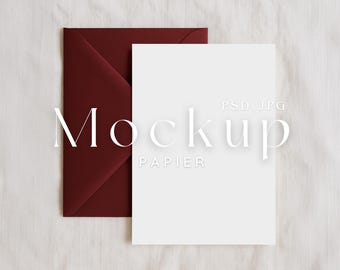 Puede incluir: Una maqueta con un sobre burdeos y una tarjeta blanca en blanco, sobre un fondo blanco texturizado. La palabra "Mockup" se muestra en una fuente delicada, con "PAPIER" debajo. La imagen es un archivo PSD.JPG.