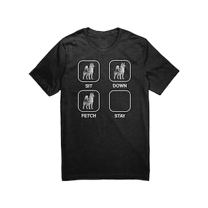 Może przedstawiać: Szary t-shirt z białym nadrukiem psa w czterech różnych pozach. Pozy są oznaczone jako "Sit", "Down", "Fetch" i "Stay".