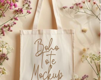 May include: White canvas tote bag with the text "boho tote mockup" in brown script font. The bag is surrounded by white and pink flowers.