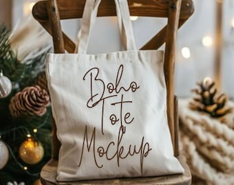 Puede incluir: Un bolso de tela de color crema con dos asas superiores. La parte frontal del bolso presenta el texto marrón "Boho Tote Mockup" escrito en una fuente cursiva. El bolso se muestra colgado en el respaldo de una silla de madera.