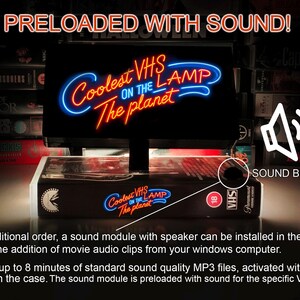 May include: A black VHS lamp with a neon sign that reads "Coolest VHS on the Lamp The Planet". The lamp is sitting on top of a stack of VHS tapes. A white speaker icon with the text "Sound Button" is in the upper right corner of the image. The lamp has a button on the side to activate the sound module.
