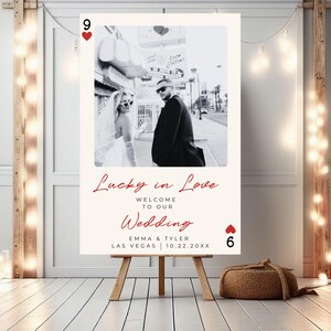 Puede incluir: Cartel de bienvenida de boda con una foto en blanco y negro de una pareja. El cartel dice "Lucky in Love, Welcome to our Wedding" con los nombres y la fecha de la pareja. El cartel est&aacute; sobre un caballete de madera.
