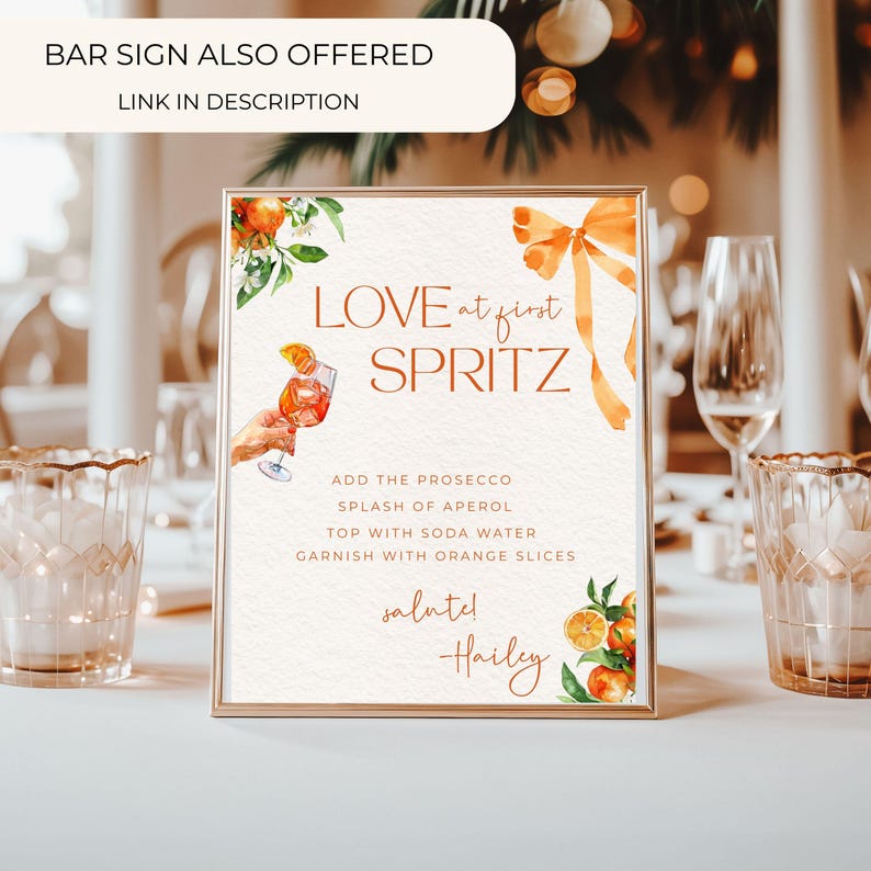 Puede incluir: Un letrero rectangular con marco dorado que dice "LOVE at first SPRITZ". Incluye ilustraciones de acuarela de naranjas y un c&oacute;ctel. Tambi&eacute;n se ve el texto "ADD THE PROSECCO" y "GARNISH WITH ORANGE SLICES".