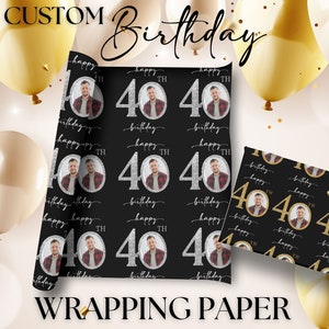 May include: Black and gold wrapping paper with a silver glitter 40 and the words "Happy 40th Birthday". The paper features a repeating pattern of a man's face in a circle.