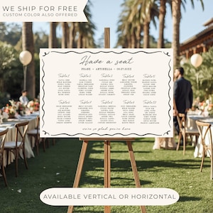May include: A cream-colored wedding seating chart on a wooden easel. The chart features elegant calligraphy with the names of guests organized by table. The text includes "Have a seat" and "Frank + Antonella 06.27.20XX". The bottom reads "Available vertical or horizontal".