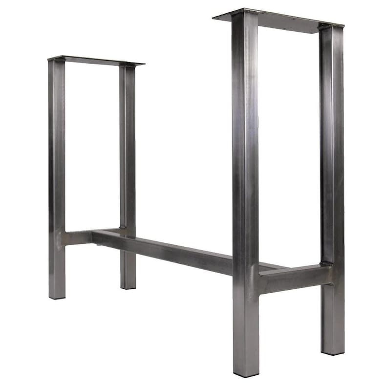 May include: A pair of metal table legs with a rectangular crossbar. The legs are made of thick, sturdy metal and have a raw, industrial finish.