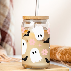 May include: A glass jar with a bamboo lid and a straw filled with a light brown beverage. The jar has a Halloween-themed design with white ghosts, black bats, and pink flowers.