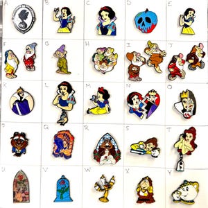May include: Collection of enamel pins featuring characters and elements from a fairy tale. Includes Snow White, the Evil Queen, the Beast, and other iconic figures. The pins are colorful and detailed, with various shapes and sizes.