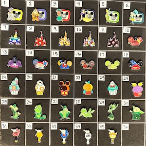 May include: A collection of 36 enamel pins featuring various Disney characters and icons. The pins showcase characters like Stitch, Mickey Mouse, and Tinkerbell, as well as castle and cupcake designs. The pins are arranged on a black surface.