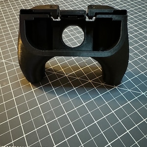 May include: A black 3D printed handheld game controller with a circular opening in the center.