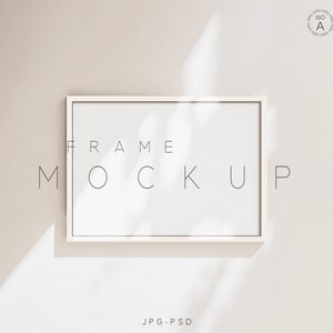Puede incluir: Maqueta de marco blanco con el texto "FRAME MOCKUP" en un estilo minimalista sobre un fondo beige claro.