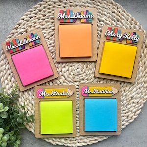 May include: Five wooden notepads with colourful sticky notes and personalised names. Each notepad has a pencil and stack of books design. The names are "Mrs. Devona", "Mrs. Lehmann", "Mary Kelly", "Mrs. Linder", and "Mrs. Matthias".