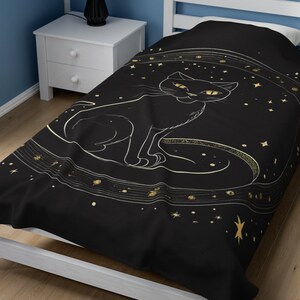 May include: Black twin bed duvet cover with a gold outline of a cat sitting on a crescent moon with stars in the background.