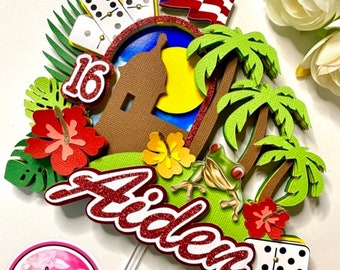 May include: A red, white, and blue Puerto Rican flag with a green palm tree and a brown building with a yellow sun behind it. The number 16 is in red glitter and the name Aiden is in red glitter. There are dominoes and a green frog on the cake topper.