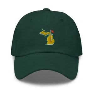 Op de afbeelding: Een donkergroene baseballpet met een geborduurde gele omtrek van de staat Michigan met een rode vlag op een witte paal.