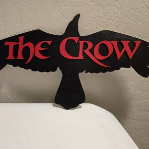 May include: Black silhouette of a crow with the words "The Crow" in red lettering.