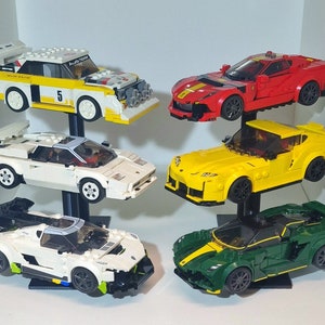 May include: A display stand with six different Lego car models. The cars are white, red, yellow, green, and black. The stand is black and has a white base.