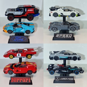 May include: Collection of toy race cars, including a gray and red off-road vehicle, a blue and orange Ford GT, a white and gray sports car, a gray sports car with "SPEED CHAMPIONS" text, a red race car with a white stripe, a red Ferrari, and a black and teal AMG.