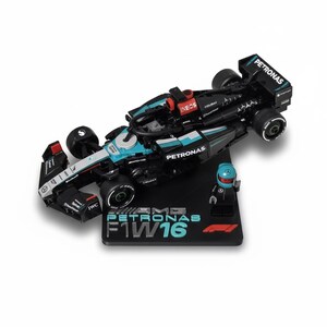 May include: A black and teal Formula 1 race car model with the word "PETRONAS" on the side. The model includes a small figure of a driver and sits on a black base with the text "AMG PETRONAS F1 W16".