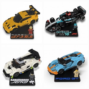 May include: Four toy car models, including a yellow Porsche GT3 RS, a black Mercedes-AMG Petronas F1 W16, a white Koenigsegg Jesko, and a blue Ford GT. Each car is on a black base with the car's name.