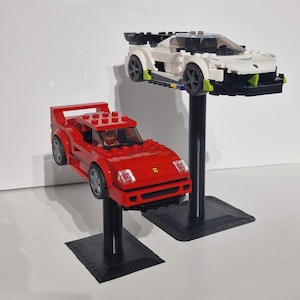 May include: Two Lego toy cars on display stands. A red Ferrari F40 and a white sports car with green accents.