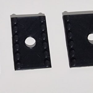 May include: Three black plastic spacers with a hole in the center. The spacers are different sizes.