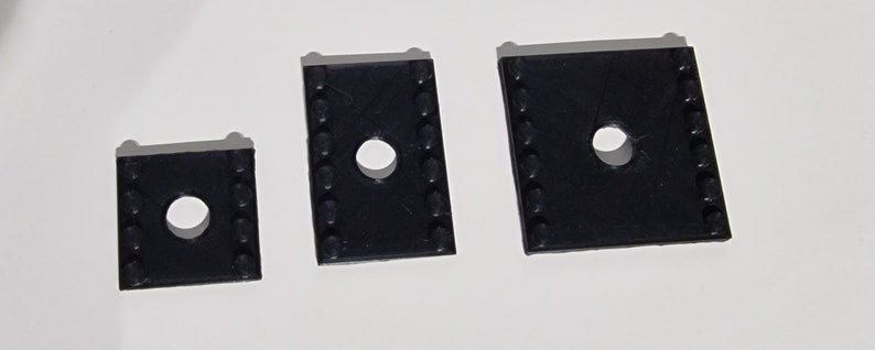 May include: Three black plastic spacers with a hole in the center. The spacers are different sizes.