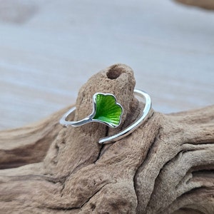 May include: A silver ring with a green enamel ginkgo leaf design. The ring is open and adjustable.