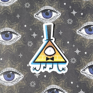 Puede incluir: Una pegatina con un triángulo amarillo con sombrero de copa, pajarita y un ojo. El fondo es gris oscuro con ilustraciones repetidas de ojos y estrellas.