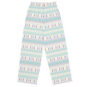 May include: Light blue pajama trousers featuring a repeating pattern of colourful Easter bunny figures. The design includes rows of bunnies in yellow, purple, and pink, interspersed with geometric shapes and stripes. The trousers are made of a soft material.