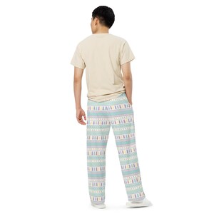 May include: Light blue pyjama trousers featuring a repeating pattern of bunnies, stars, and geometric shapes in pastel colours. The trousers have a straight leg design and a comfortable fit.