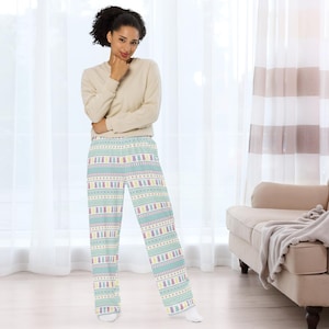 May include: A light beige long-sleeved top and pajama trousers. The trousers feature a light blue background with a repeating pattern of Easter bunnies in pastel colours. The trousers have a wide-leg design.